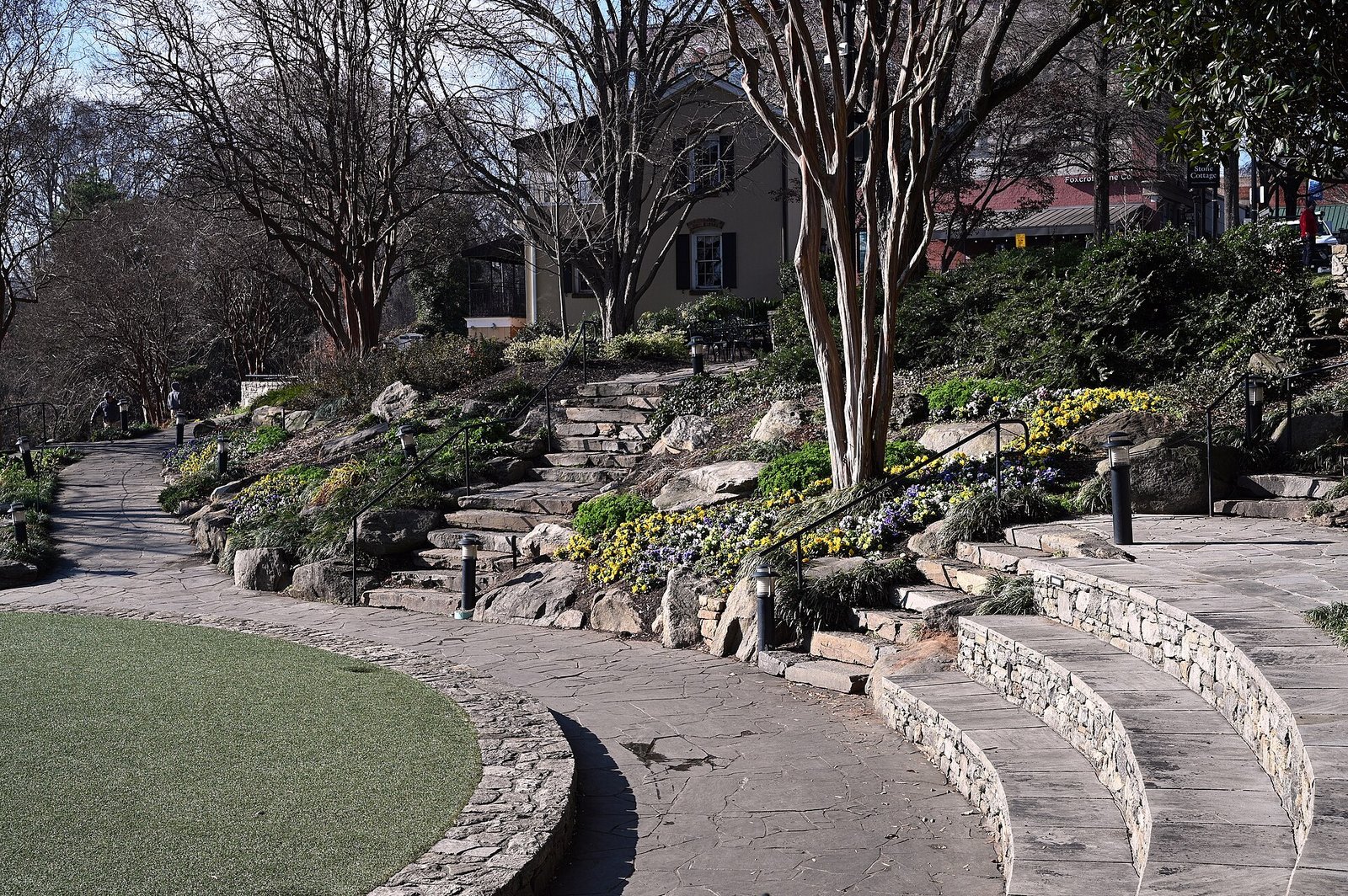 Curving stone steps and a flagstone path through landscaped gardens with yellow flowers in Falls Park