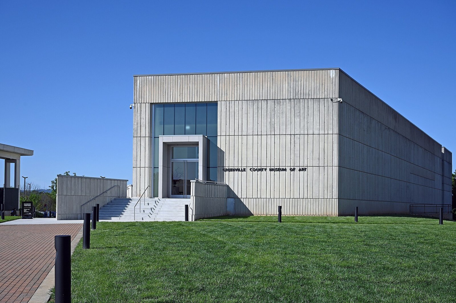 The modern concrete Greenville County Museum of Art building with its name over a glass entrance and a green lawn in front