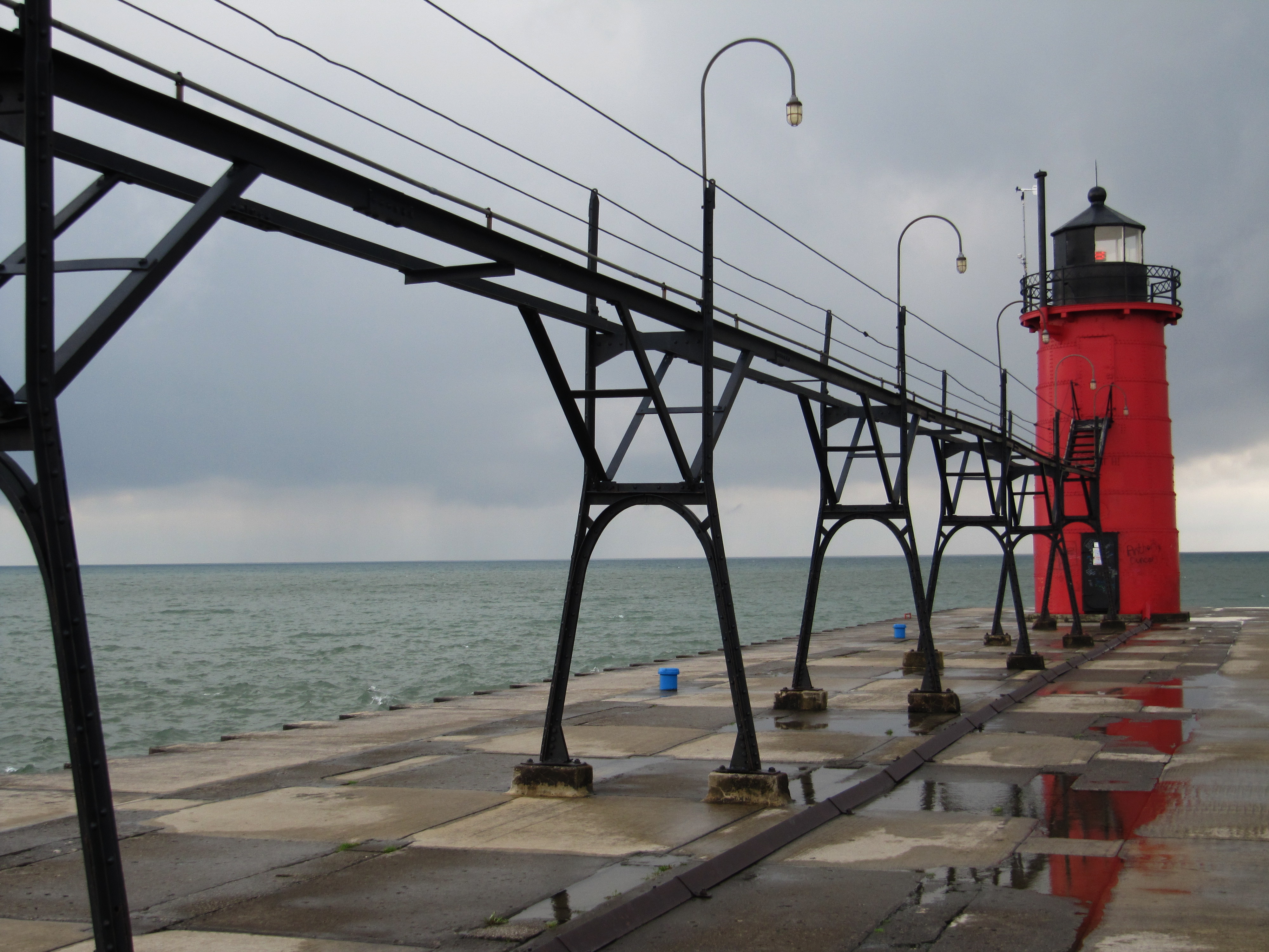 The red South Haven South Pier lighthouse and its black catwalk on an overcast day