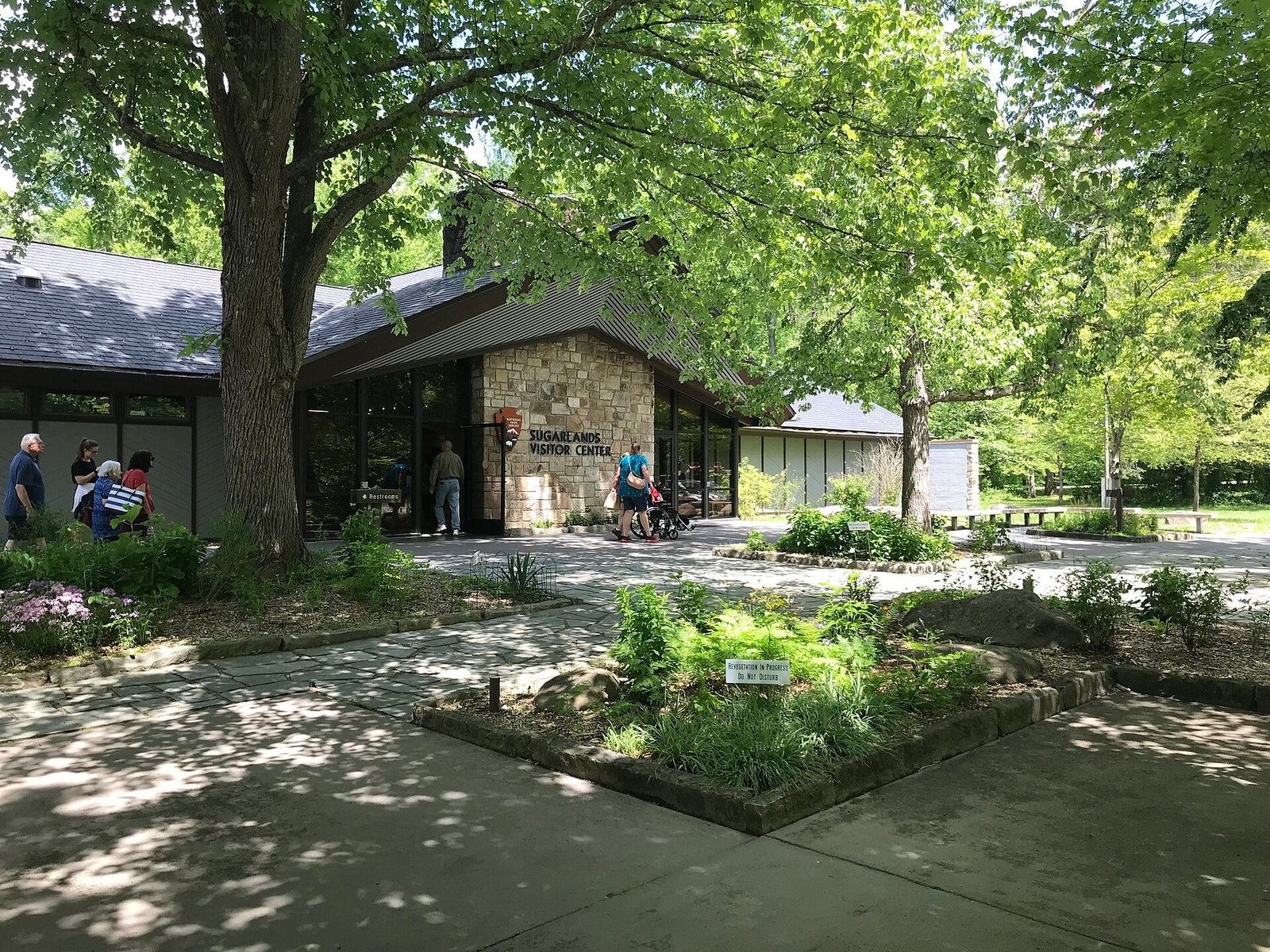 The stone and glass Sugarlands Visitor Center in Great Smoky Mountains National Park, shaded by large trees